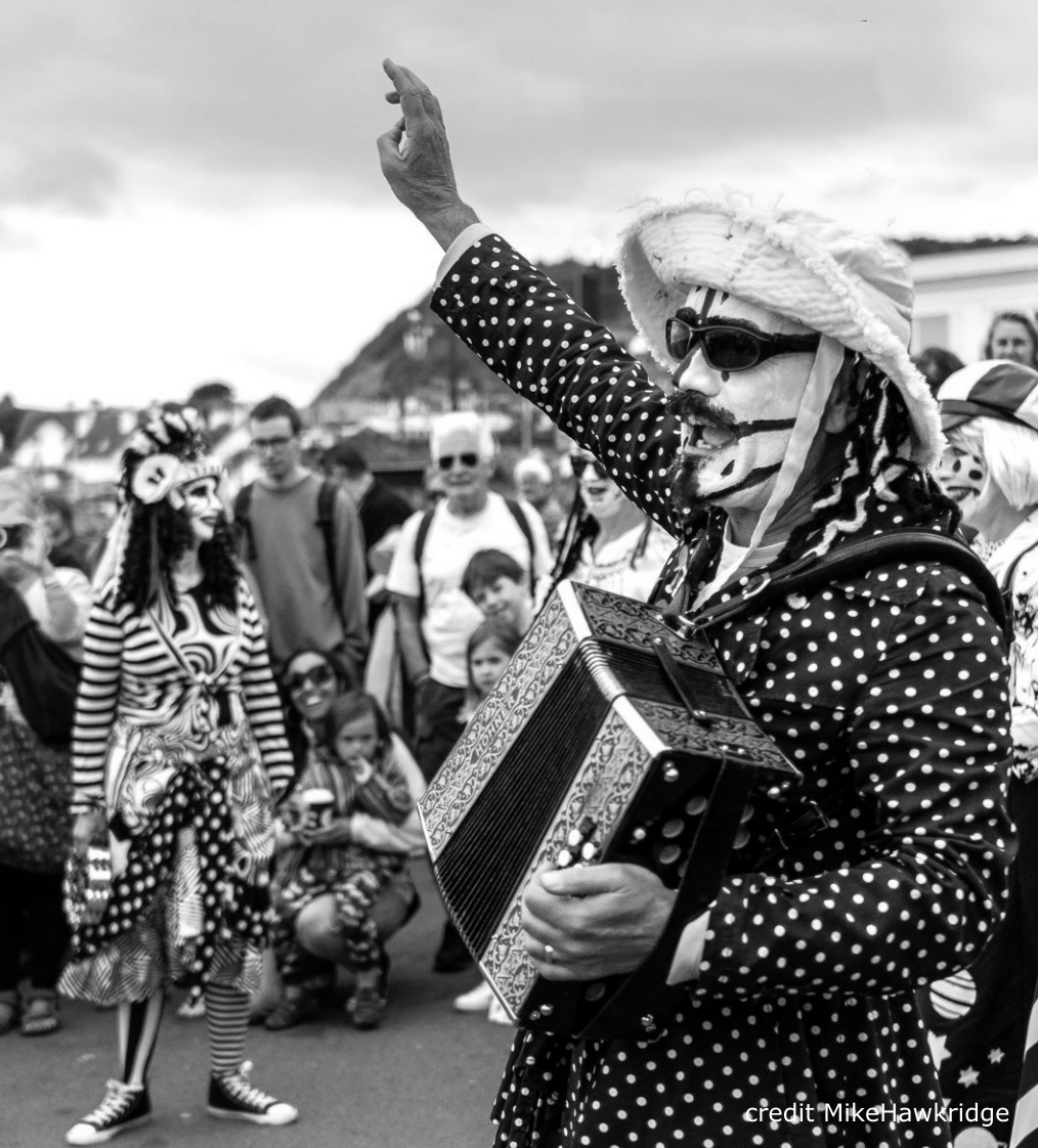 A Pig Dyke musician with a melodeon, telling a tall tale to announce the next dance